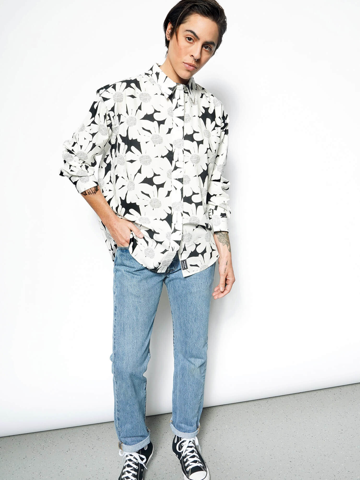 A model wearing a button up black and white floral shirt. 