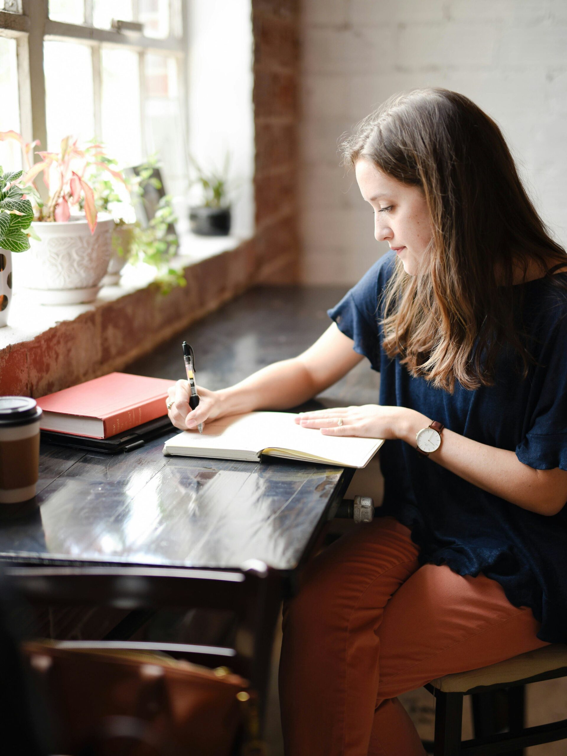 A model seated a desk, writing in their journal. 