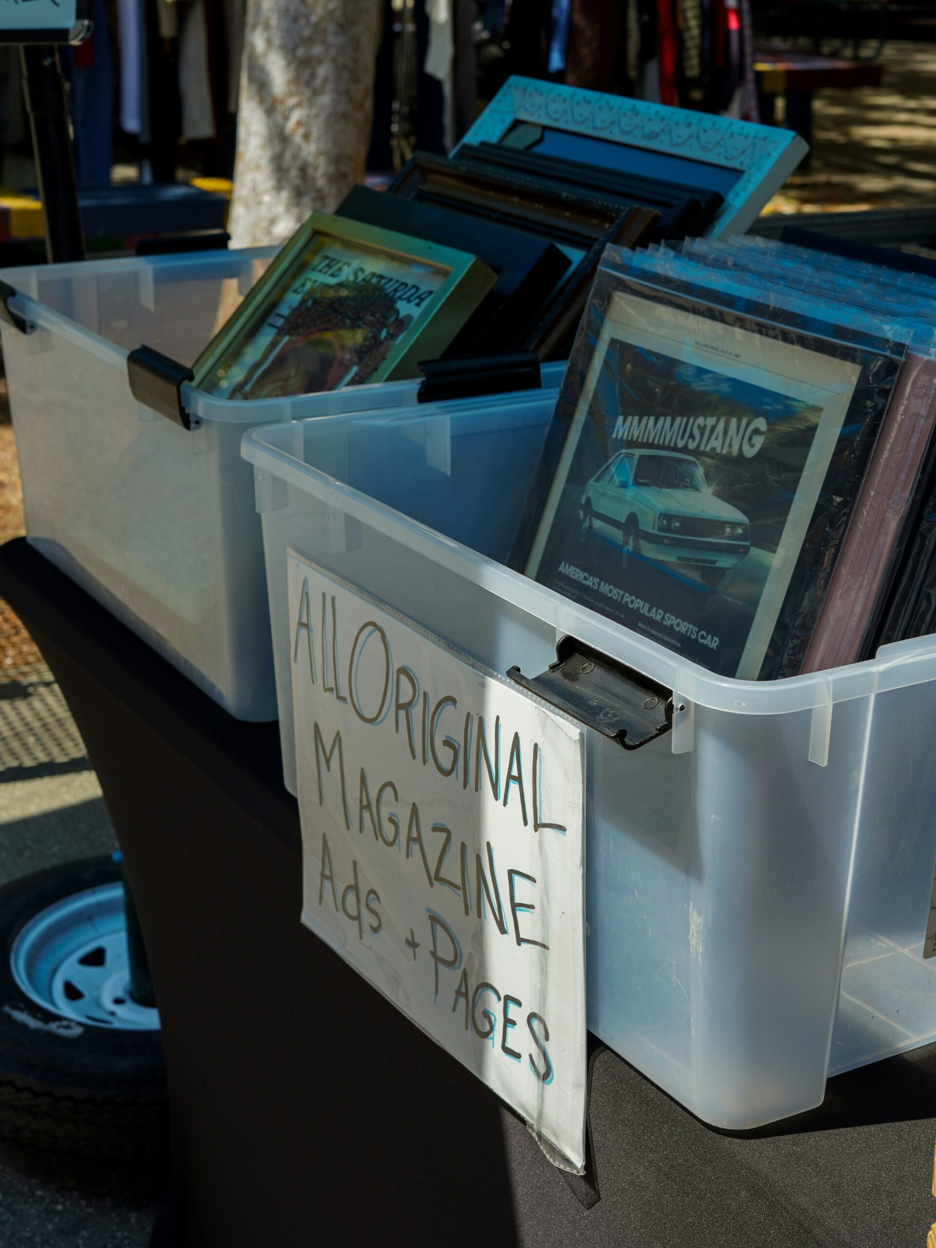 Two buckets filled with magazines with a sign in front that reads "All Original Magazine Ads + Pages"