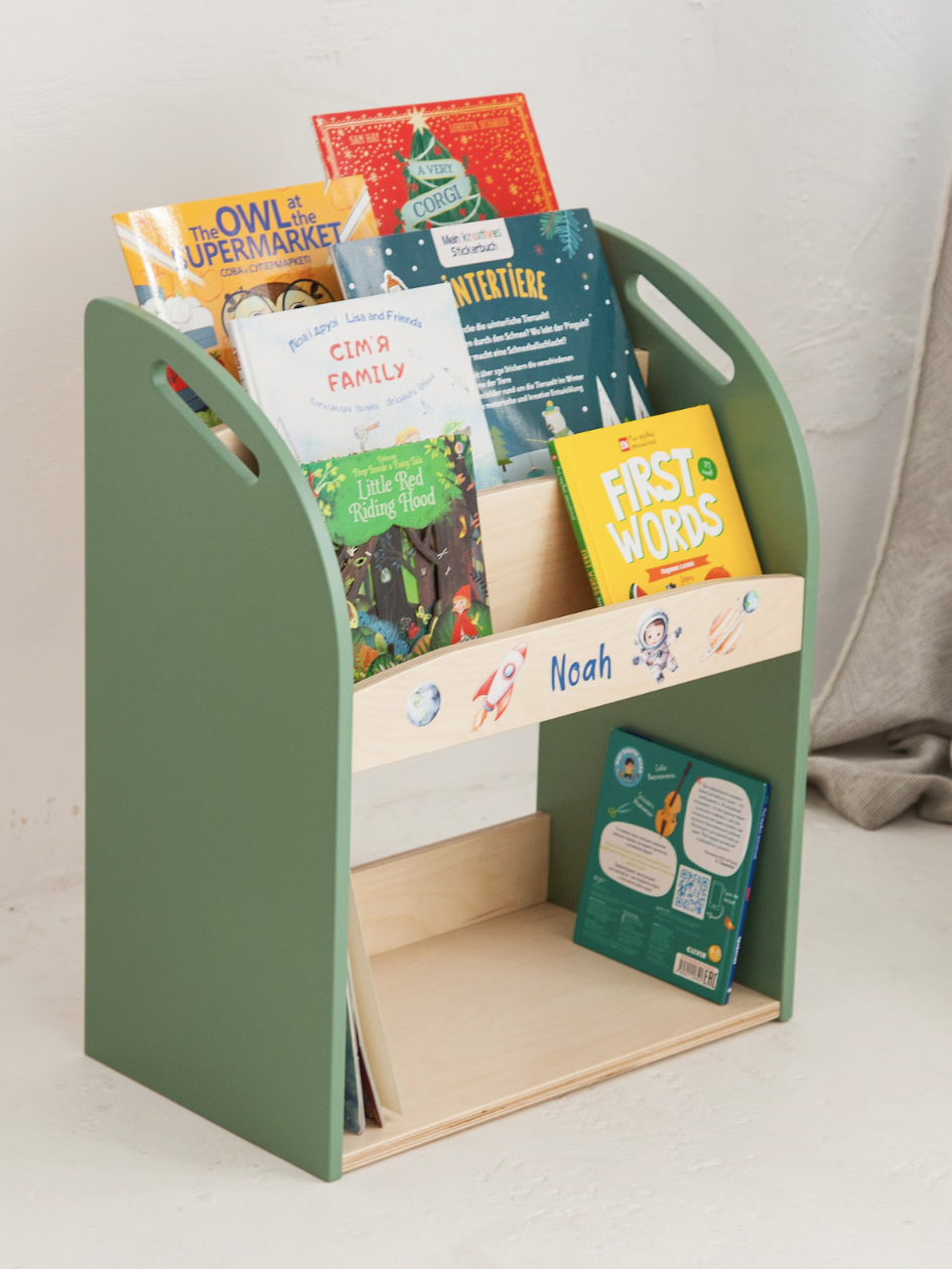 Green and wooden children's bookshelf with various picture books, some titles visible. The name "Noah" is on the front panel.