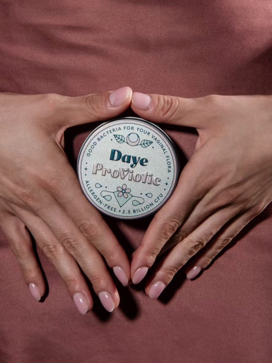 Hands form a heart shape over a jar labeled "Daye ProViotic" on a brown background.