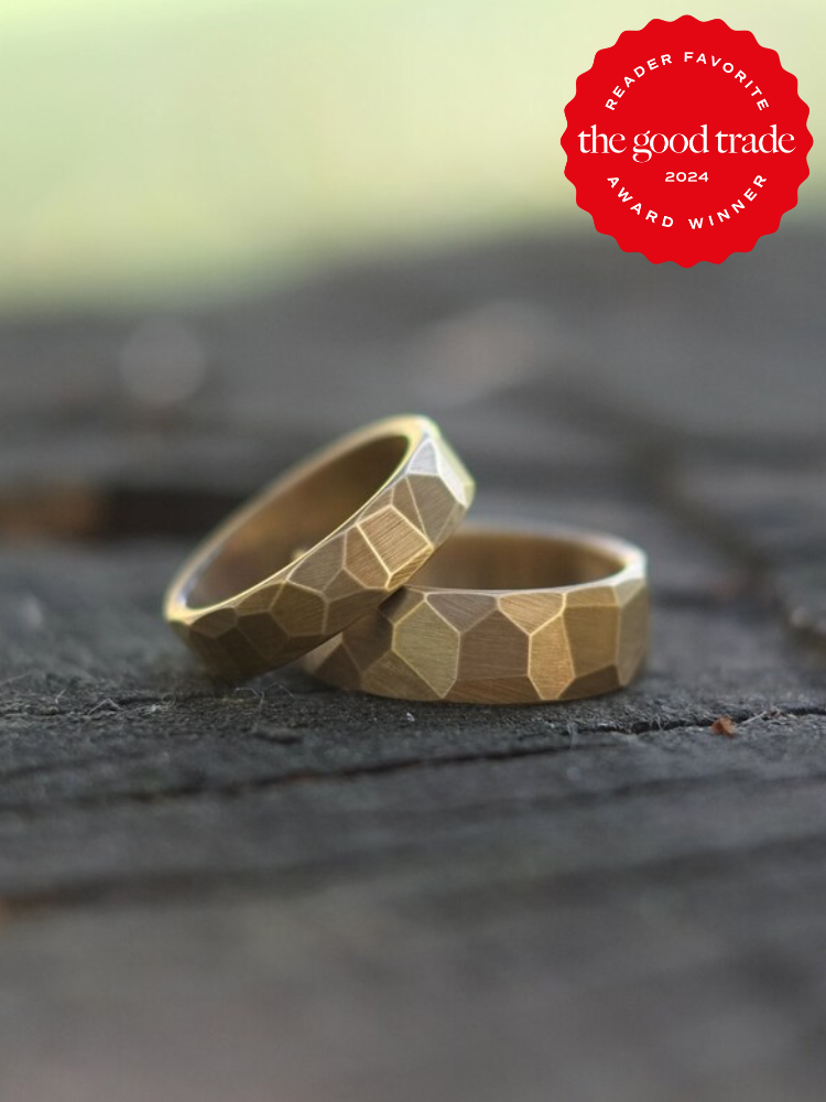 Two textured gold rings on a wooden surface with a "Reader Favorite" award badge from The Good Trade 2024 in the corner.