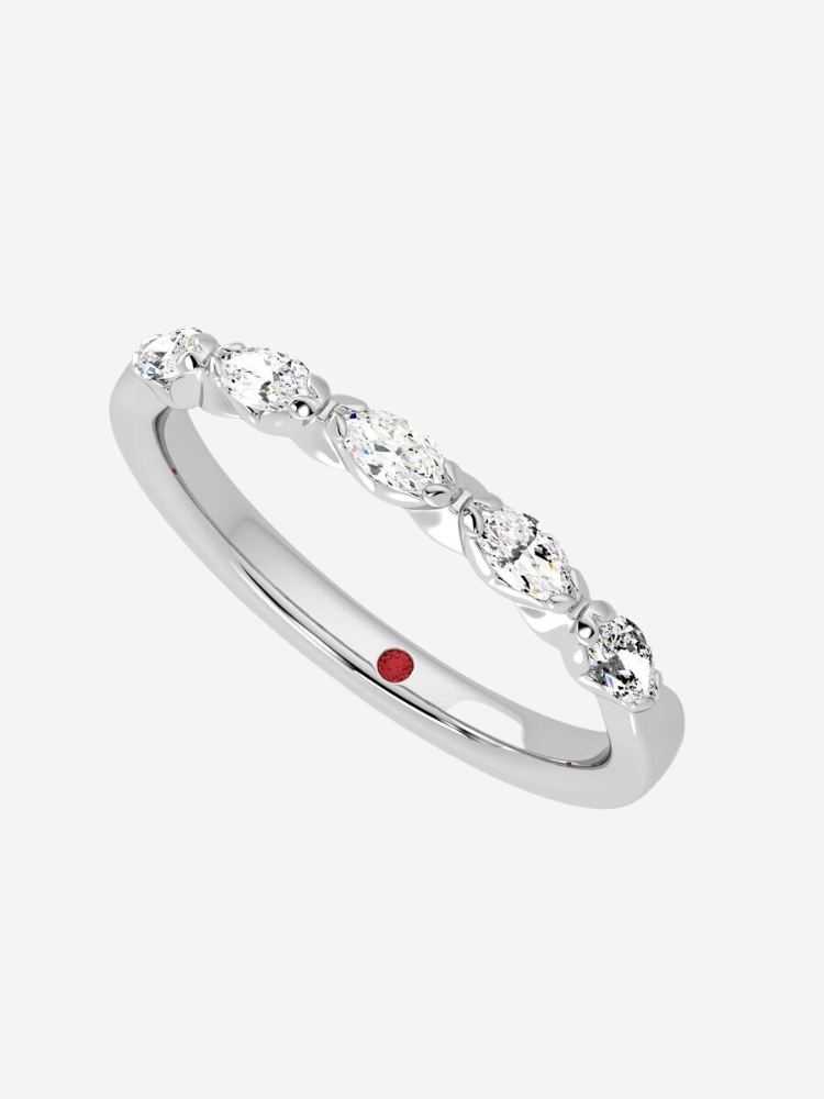 A silver ring with seven oval diamonds and a small red gem inside the band.