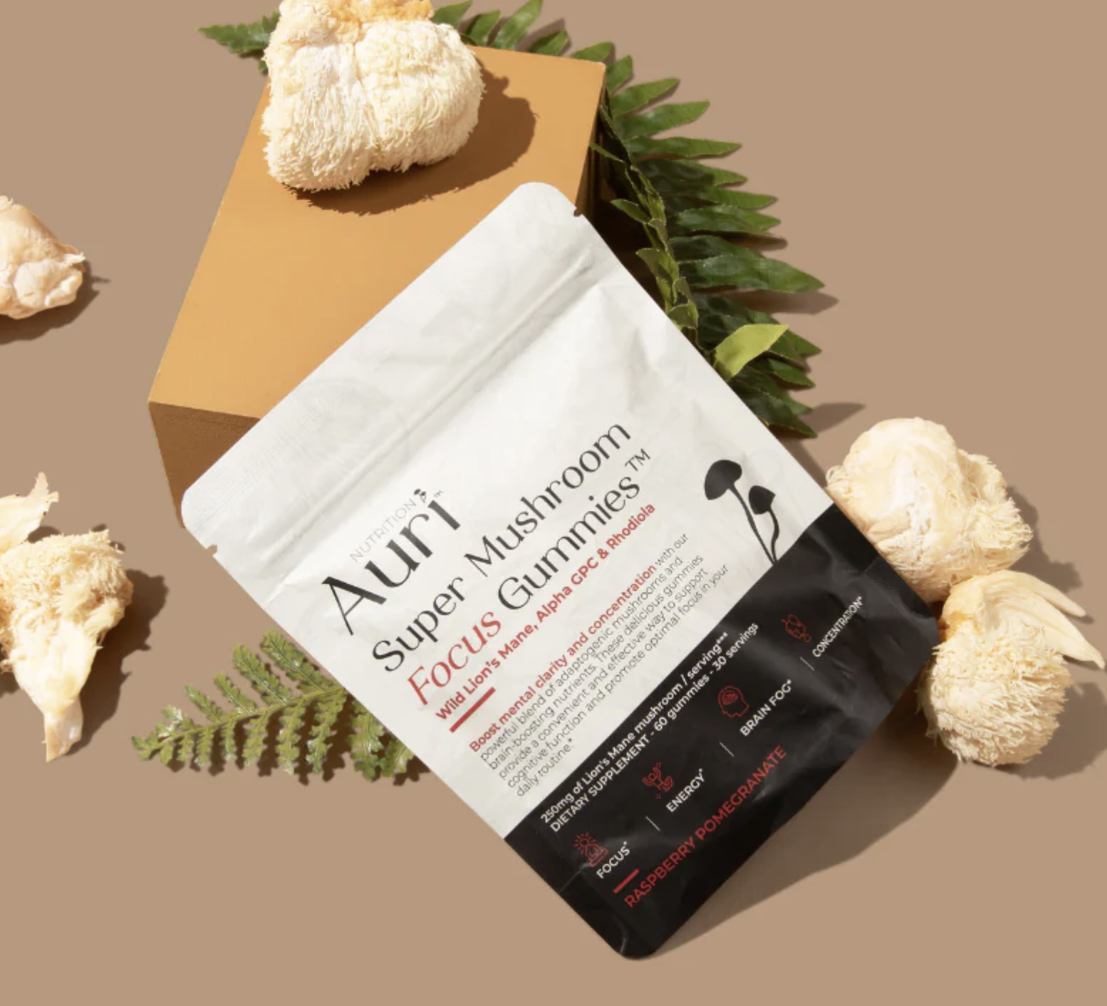 Auri Super Mushroom Focus Gummies package on a surface with Lion's Mane mushrooms and a fern leaf.