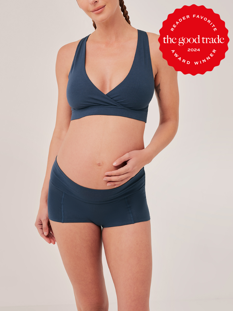 Woman wearing a matching blue sports bra and shorts set, cradling her baby bump. A badge reads "Reader Favorite, The Good Trade, 2024 Award Winner" in the top right corner.