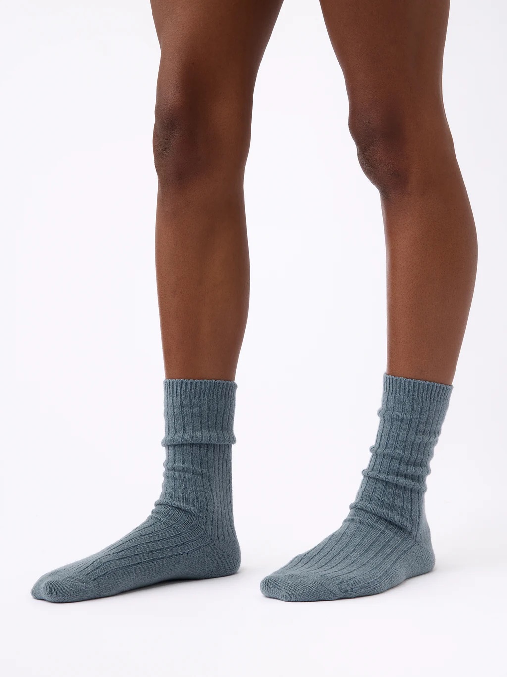 Person wearing blue organic ribbed socks standing on a white background.