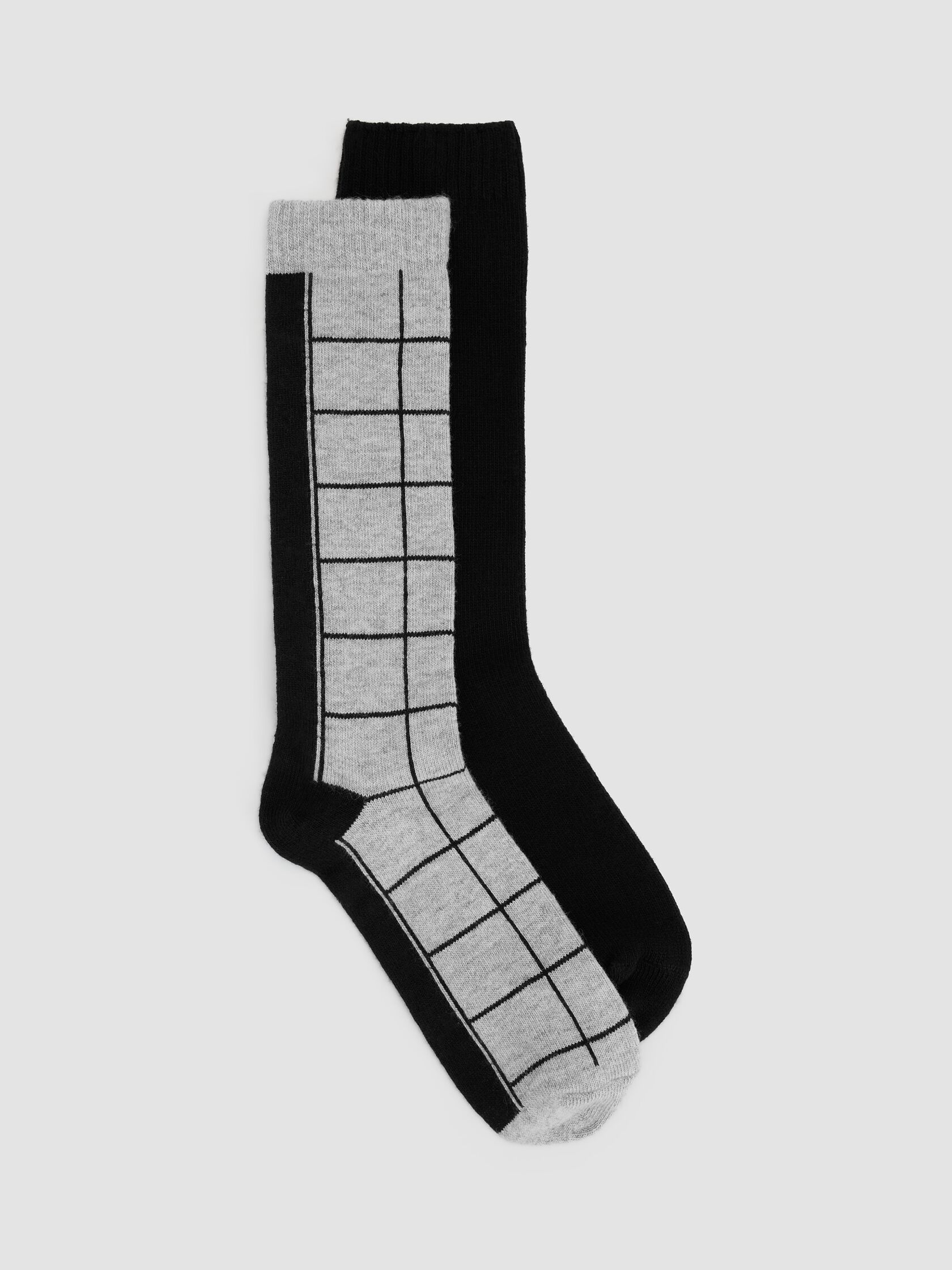 Two organic socks against a gray background. One sock is black, and the other is gray with a black grid pattern.