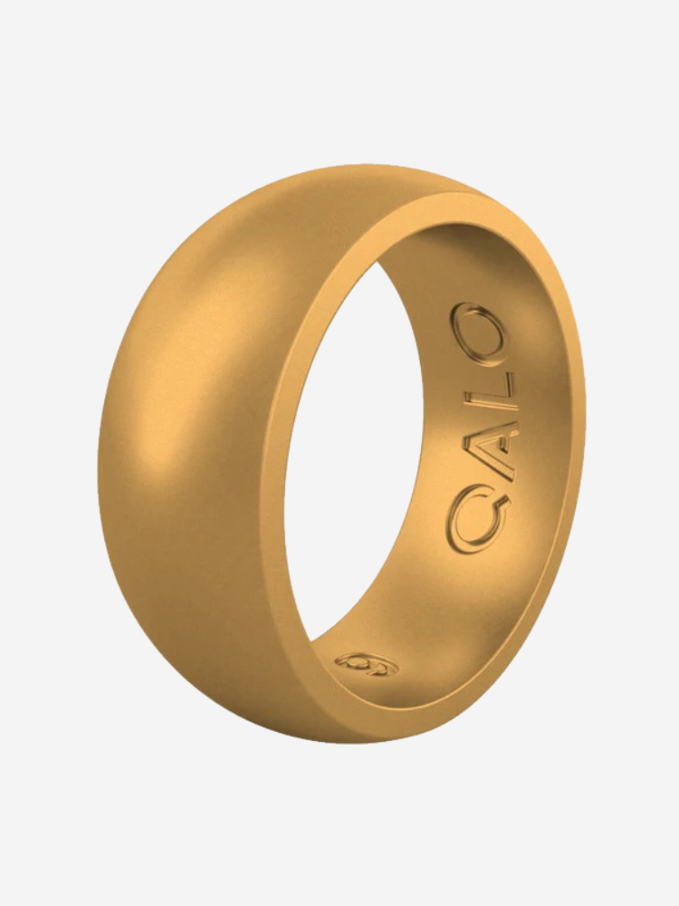 A gold-colored silicone ring with the word "QALO" engraved on the outer surface.