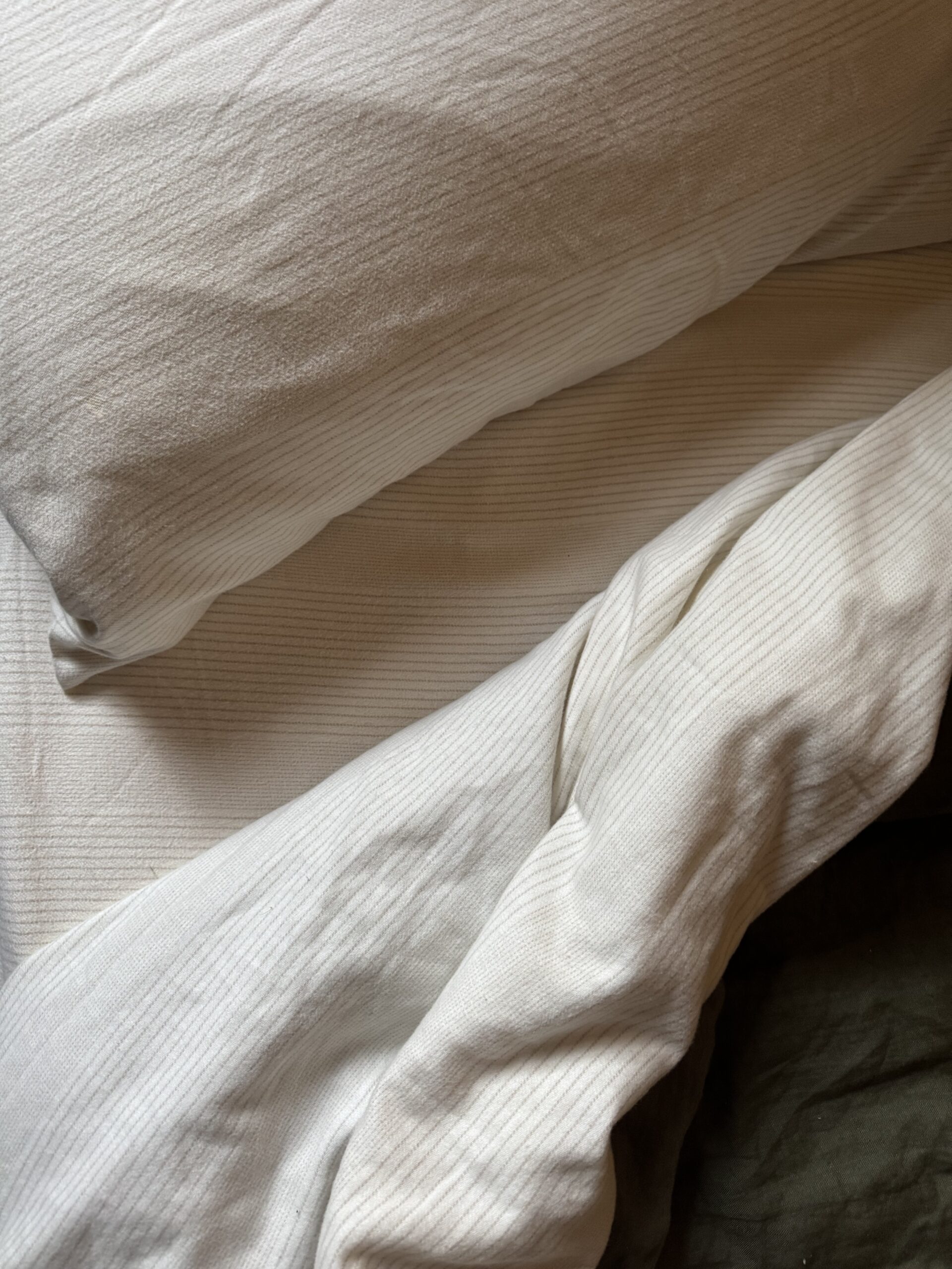 Two white pillows and a rumpled white bed sheet on a bed.