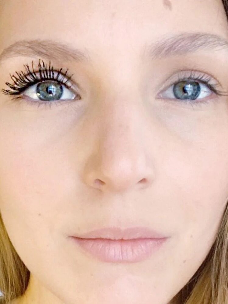 Close-up of a person with mascara applied on one eye and the other eye without makeup, showing a side-by-side comparison of eyelashes.