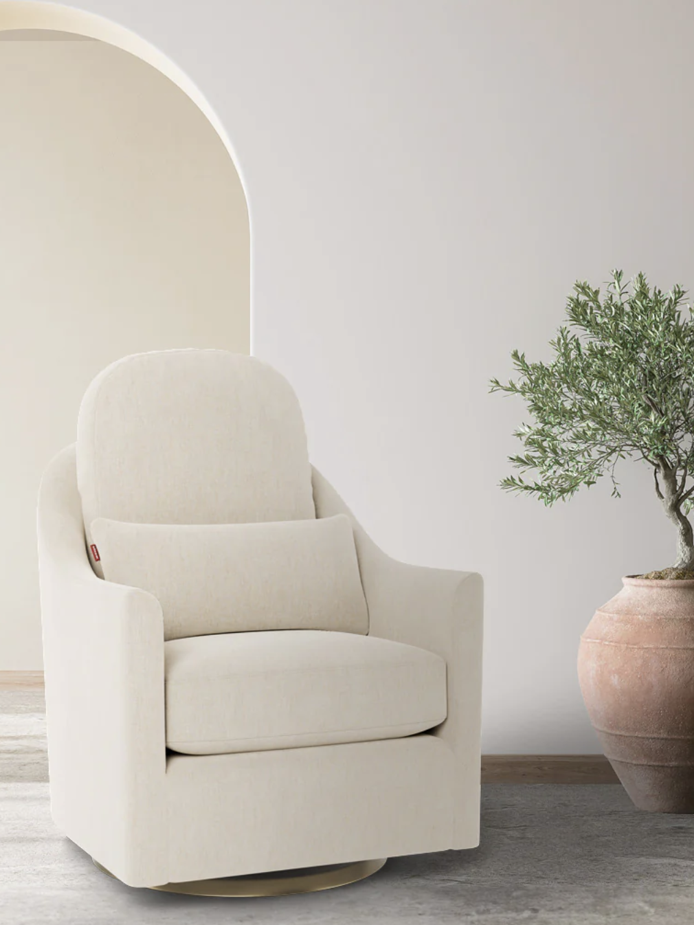 A cream-colored armchair sits in a minimalist room next to an archway and a potted plant.