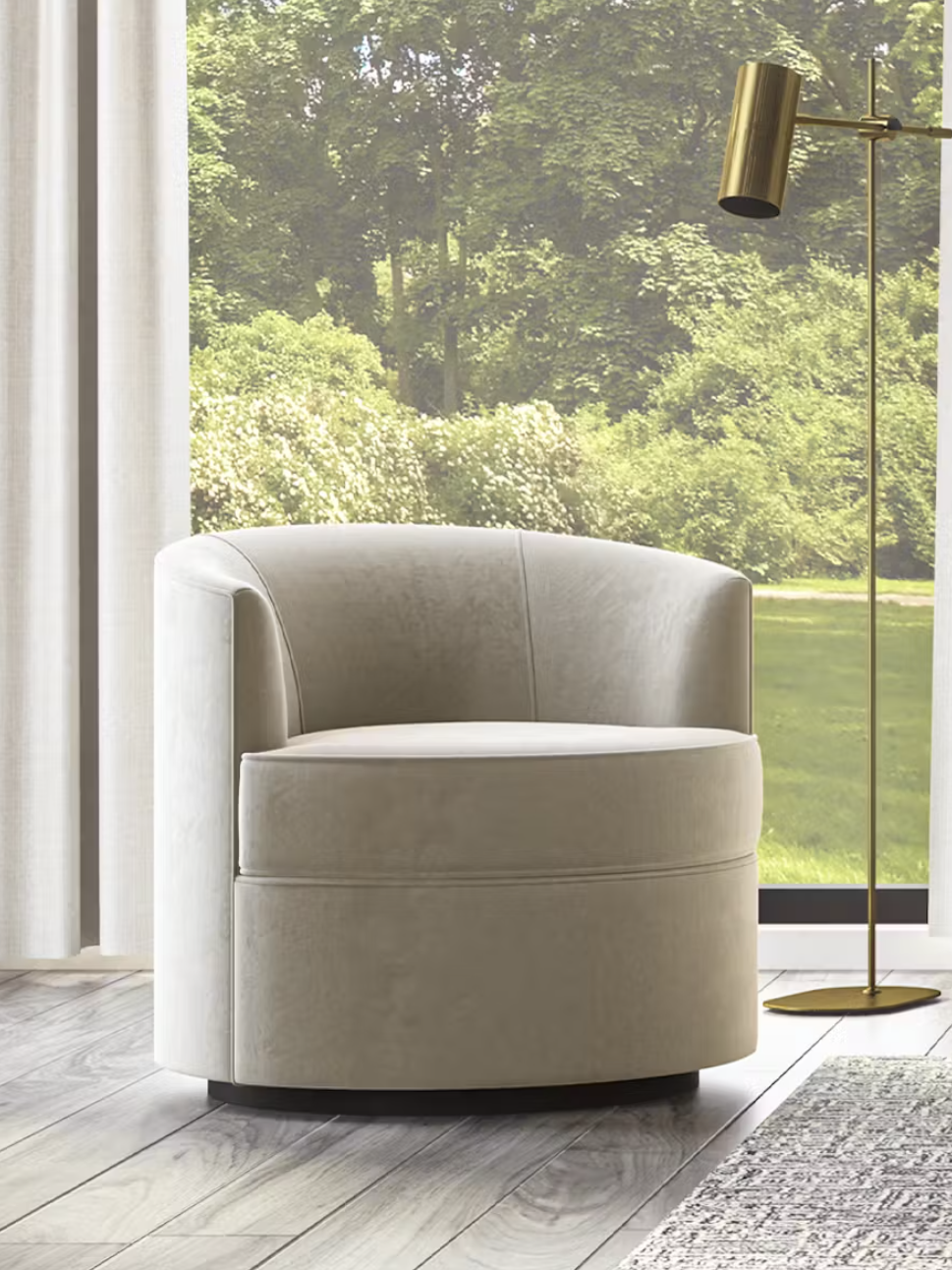 A beige velvet swivel chair sits on a wooden floor near a window with sheer curtains. A brass floor lamp stands beside it, and a garden is visible outside.