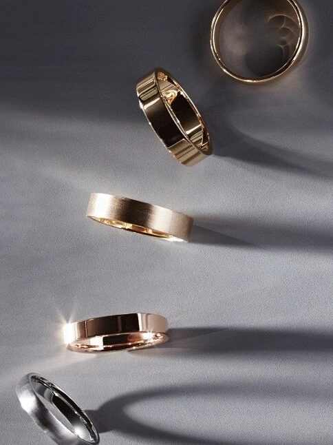 A collection of five gold and black rings displayed on a gray surface, casting shadows.