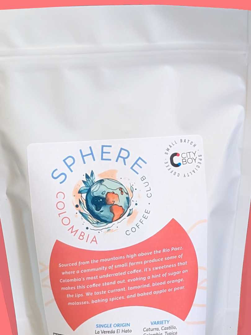 A white coffee bag labeled "Sphere Colombia Coffee Club" with descriptive text, set against a coral background.