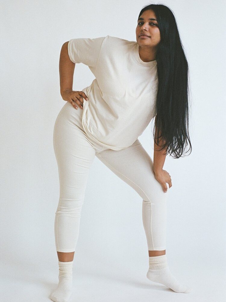 Person wearing a white outfit and socks poses against a plain white background.