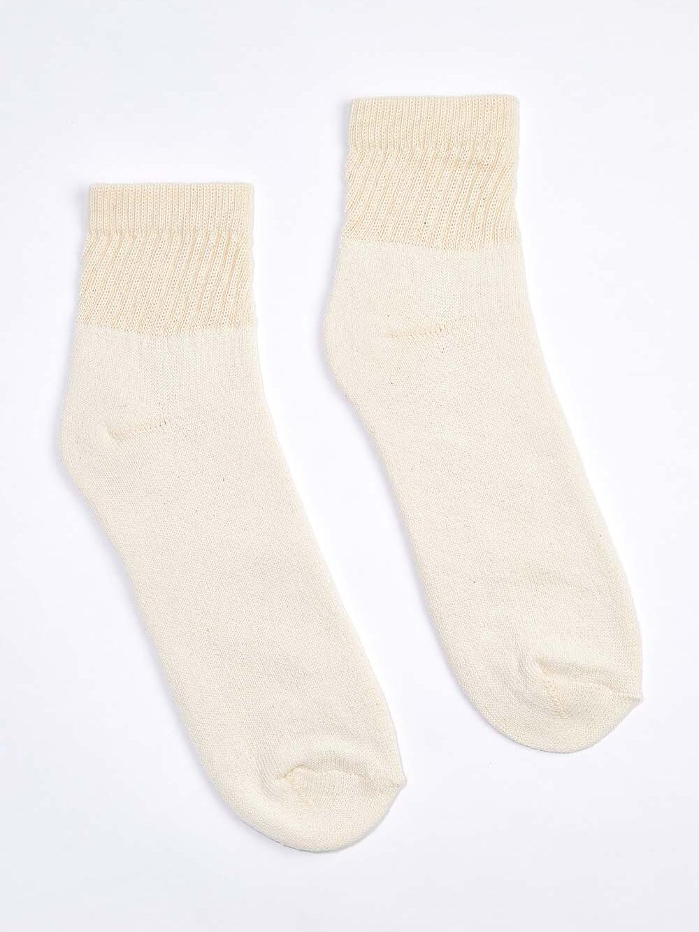 A pair of beige organic socks with ribbed cuffs rests elegantly on a plain white background.