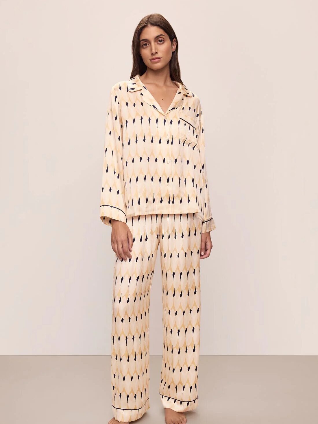 A person stands wearing a matching pajama set with a geometric pattern on a neutral background.