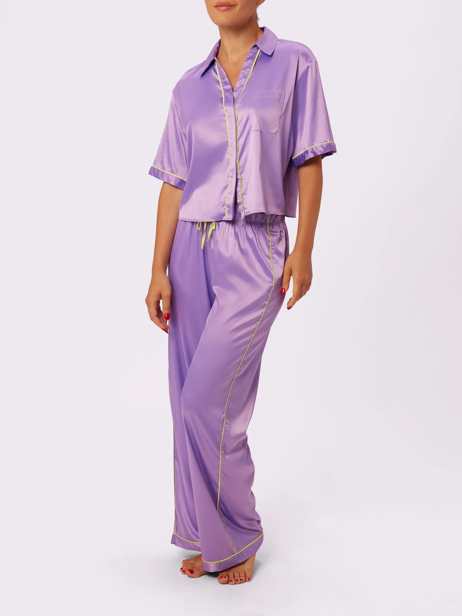 A person wearing a light purple satin pajama set with short-sleeved top and long pants, featuring a yellow trim.