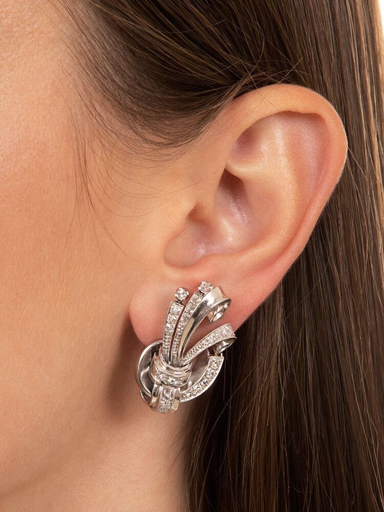 Close-up of a person's ear wearing a silver, multi-banded earring with small embedded stones.