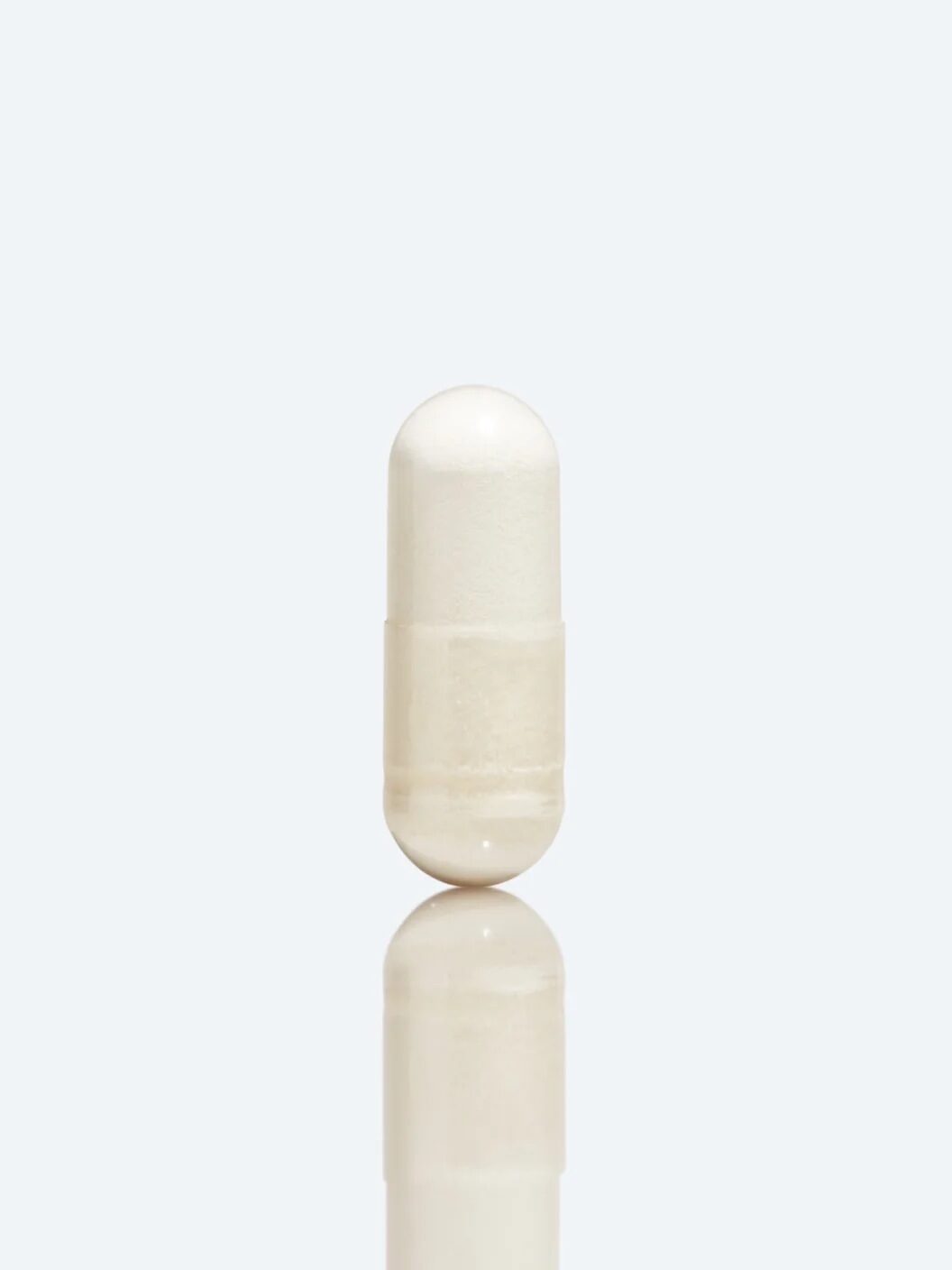 A single white capsule is centered on a plain light grey background.