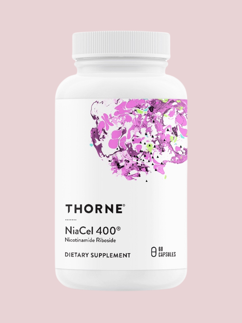 A bottle of Thorne NiaCel 400, a dietary supplement with nicotinamide riboside, against a pink background.