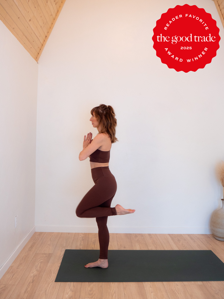 Person practicing yoga in a minimal room, standing on one leg with hands in prayer position. A red "Reader Favorite, the good trade 2023 Award Winner" emblem is on the top right.