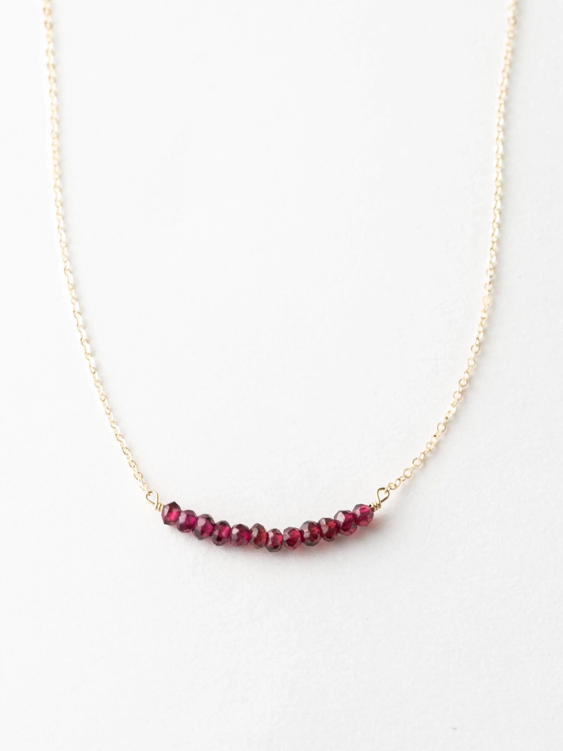 Gold necklace with small red beads arranged in a horizontal line.