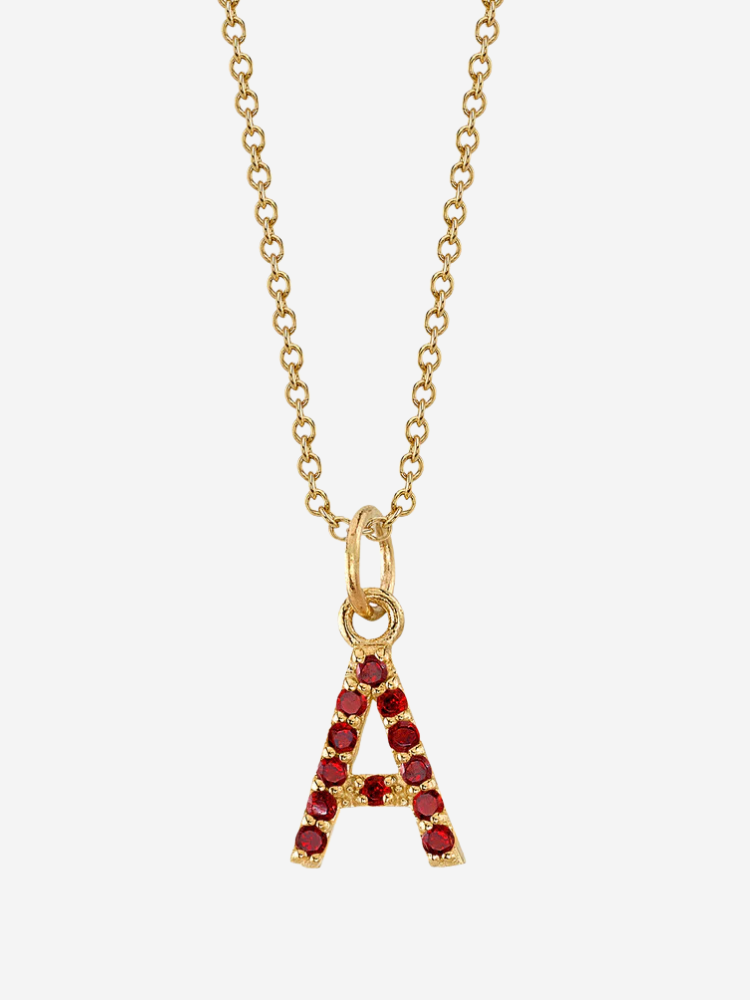 Gold necklace with a pendant shaped like the letter "A," adorned with small red gemstones.