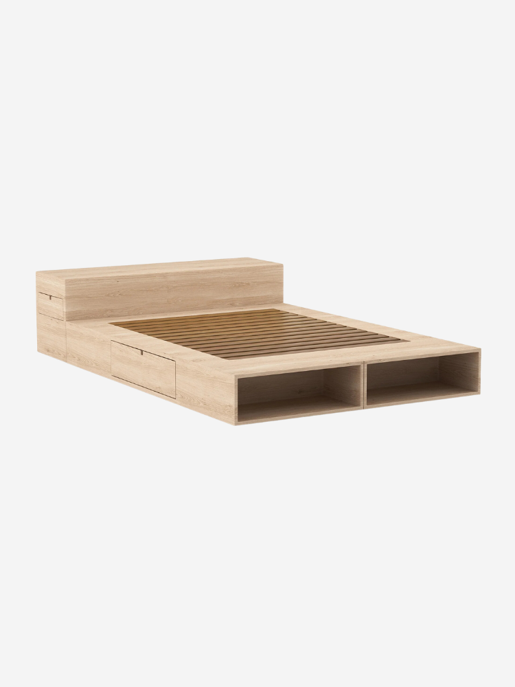 A minimalist wooden platform bed with a slatted base, integrated storage drawers, and open shelves at the foot.